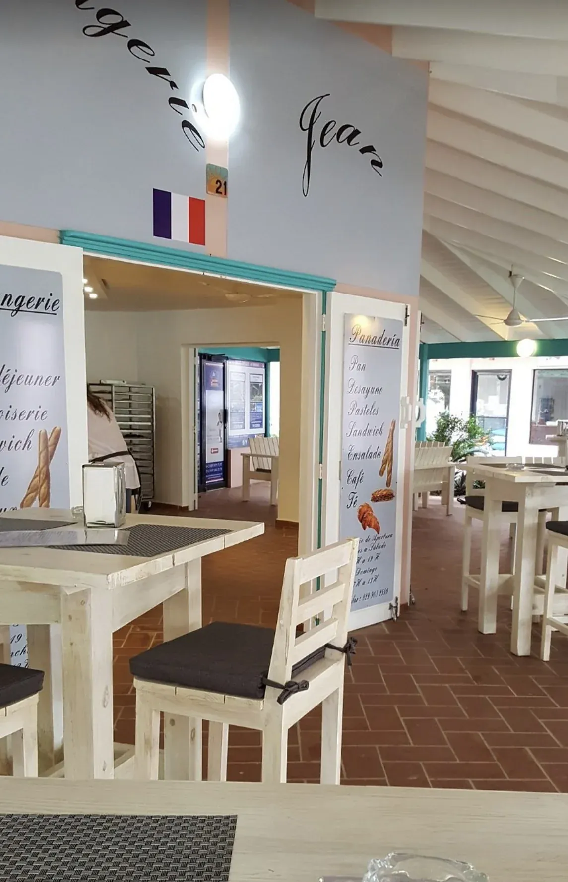 Boulangerie Jean's dining area with its sign, the French flag and the bakery menu